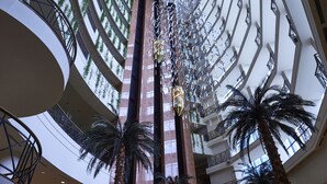 Un atrium à plusieurs niveaux, doté d’une colonne centrale, de balcons et de palmiers.