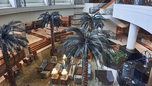 Un atrium à plusieurs niveaux, doté d’espaces de repos, de palmiers et d’un élément décoratif aquatique.