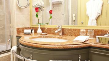 A bathroom with a marble sink, a mirror, a vase with roses, and a towel rack.