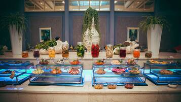 A buffet with various food options and decorative plants.