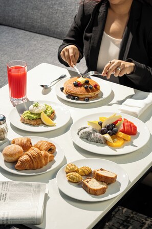 Una mesa de desayuno con diferentes alimentos y un vaso de jugo rojo.