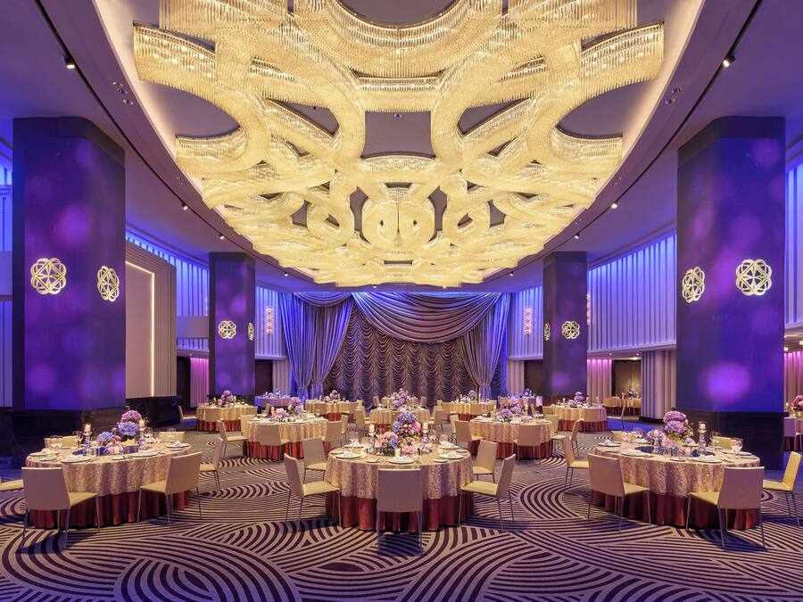 Une salle de banquet avec des tables rondes, des lustres et un tapis à motifs.