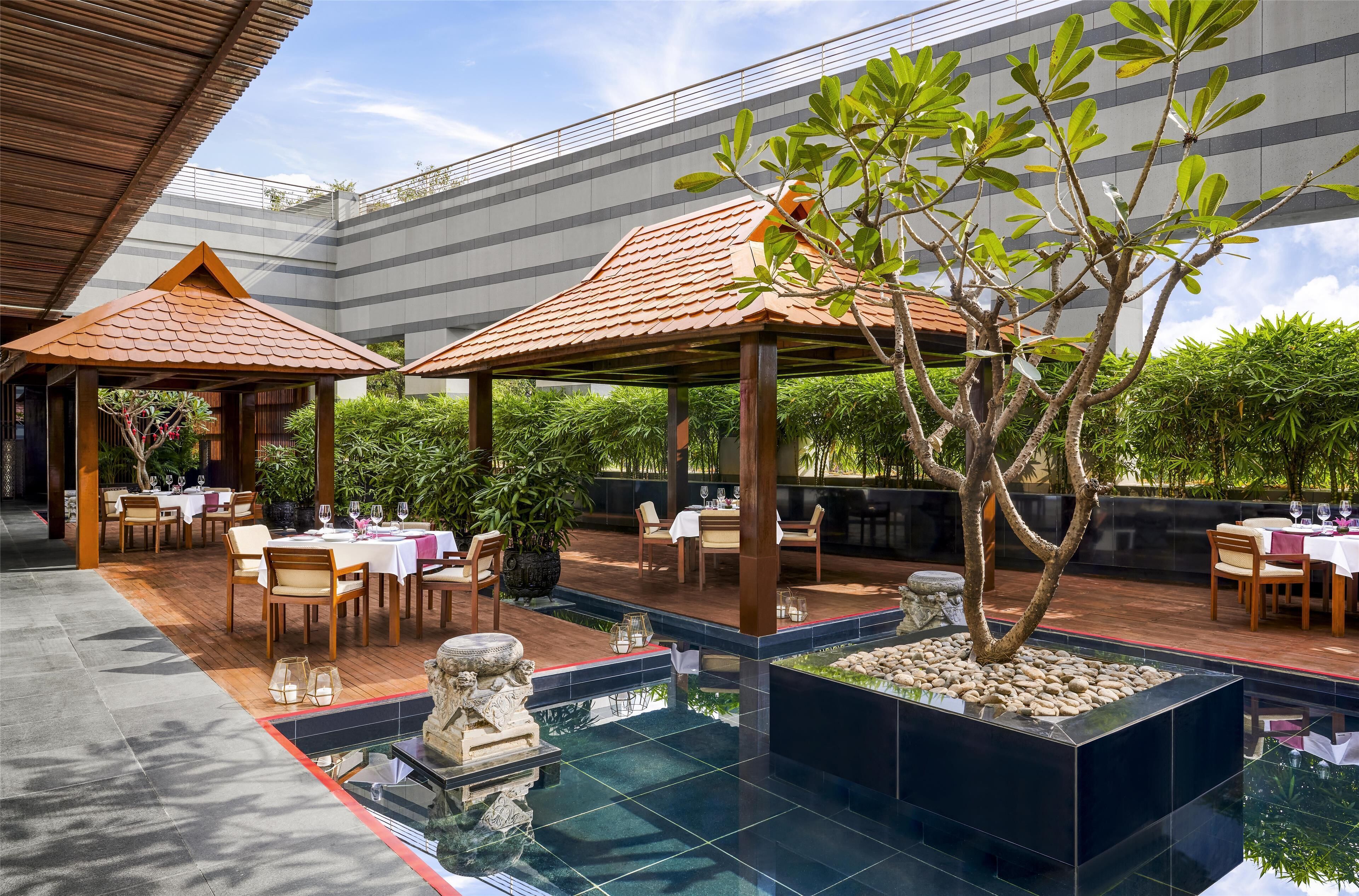 Un restaurante en la azotea con terraza, piscina y vistas a un edificio moderno.