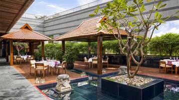 Un restaurant situé sur le toit, avec une terrasse, une piscine et une vue sur un bâtiment moderne.