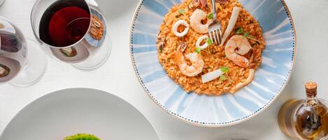 Una mesa con varios platos, incluyendo pasta, risotto de camarones, un plato de albóndigas y una ensalada.