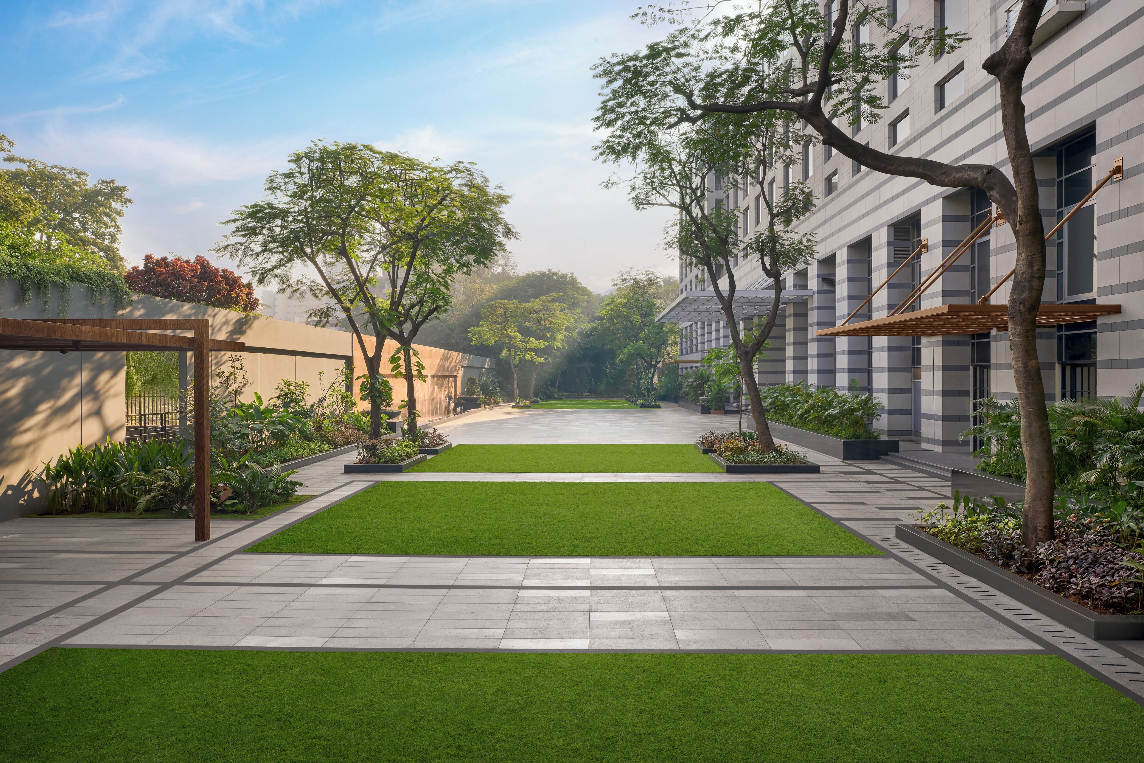 A courtyard with a central lawn, surrounded by buildings with large windows and a pergola.
