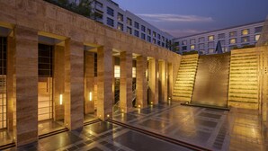 Edifici modern amb un pati interior, que destaca per una sèrie de columnes, una escala i una paret amb un disseny geomètric.