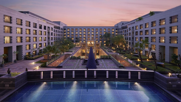 Un hotel modern amb un pati central, una piscina i diverses plantes amb balcons.