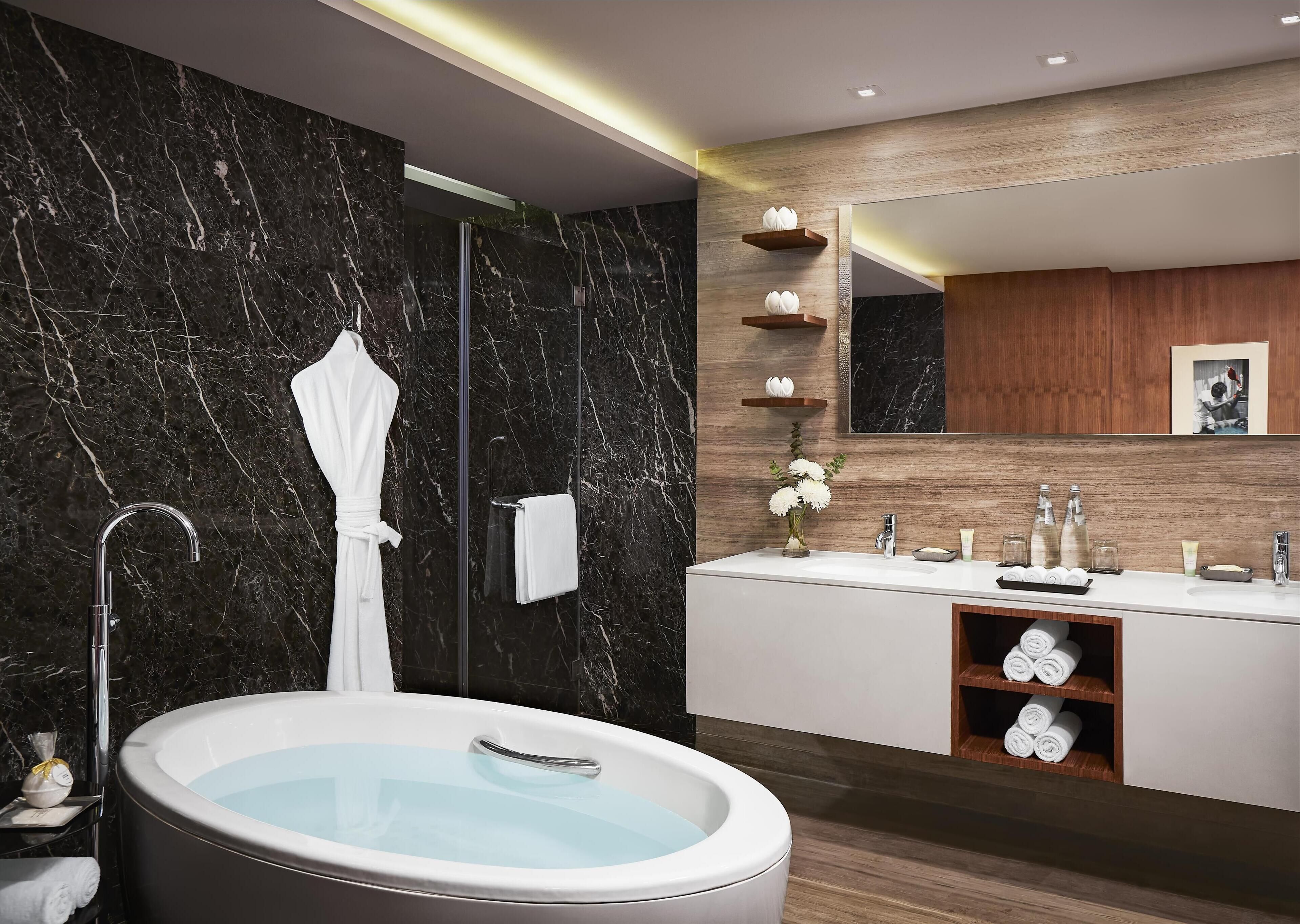 Ein modernes Badezimmer mit einer freistehenden Badewanne, einem großen Spiegel und einem Waschtisch mit doppelter Spüle.
