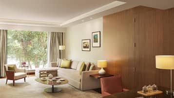 Una habitación de hotel moderna con un sofá, sillones, una mesa baja y una mesa de comedor.