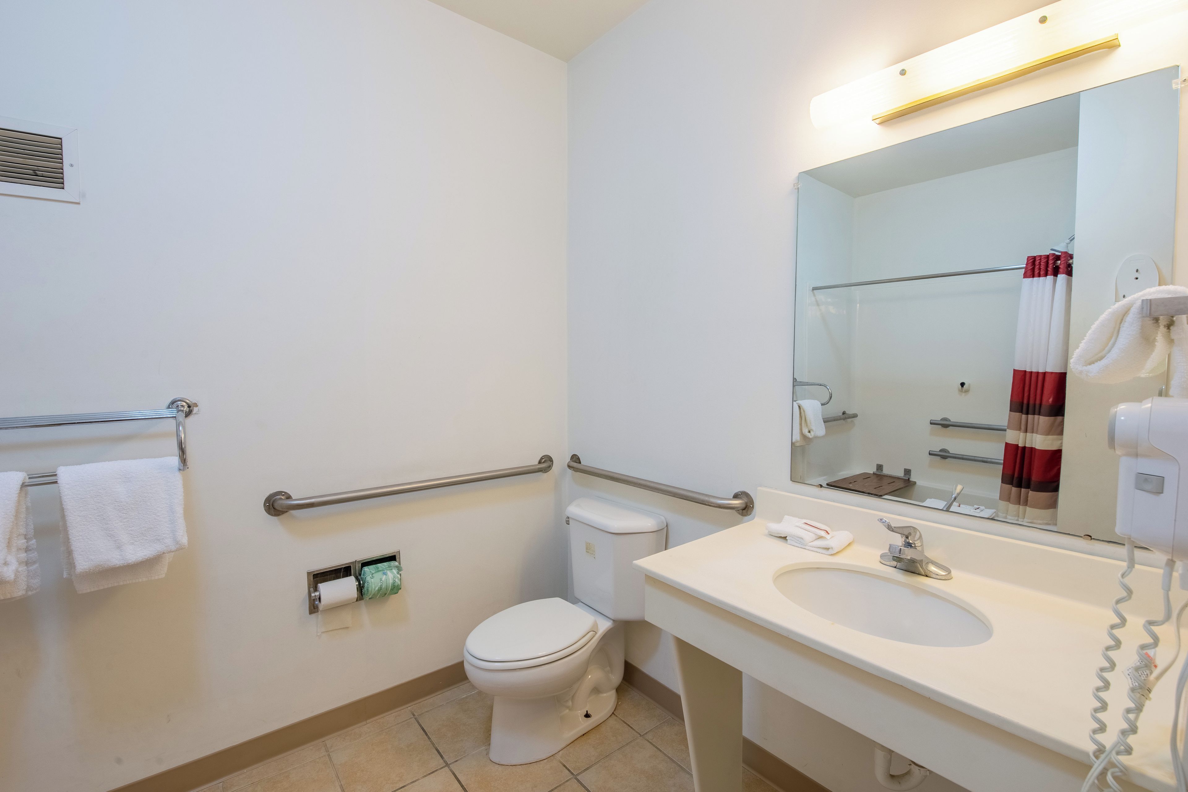 Un bagno standard in hotel con il water, bidet, lavandino e uno specchio.