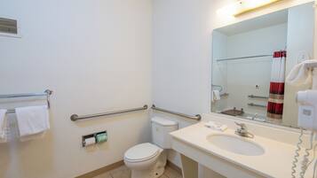 Un bagno standard in hotel con il water, bidet, lavandino e uno specchio.