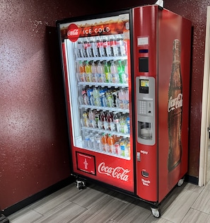 Máquina expendedora de Coca-Cola con una variedad de bebidas, incluyendo gaseosas y jugos, y un precio de $3.00 por todas las bebidas.