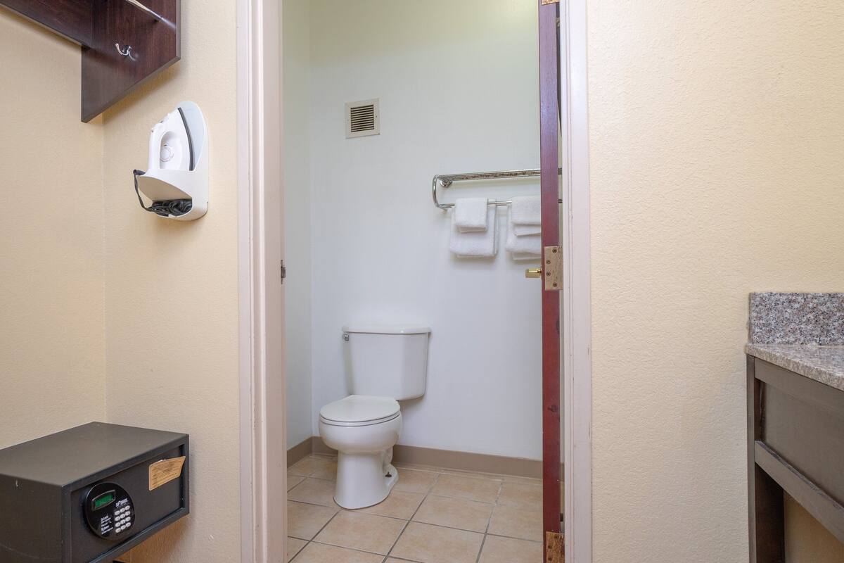 Ein kleines Badezimmer mit Toilette, Handtuchspender und einer Mikrowelle.