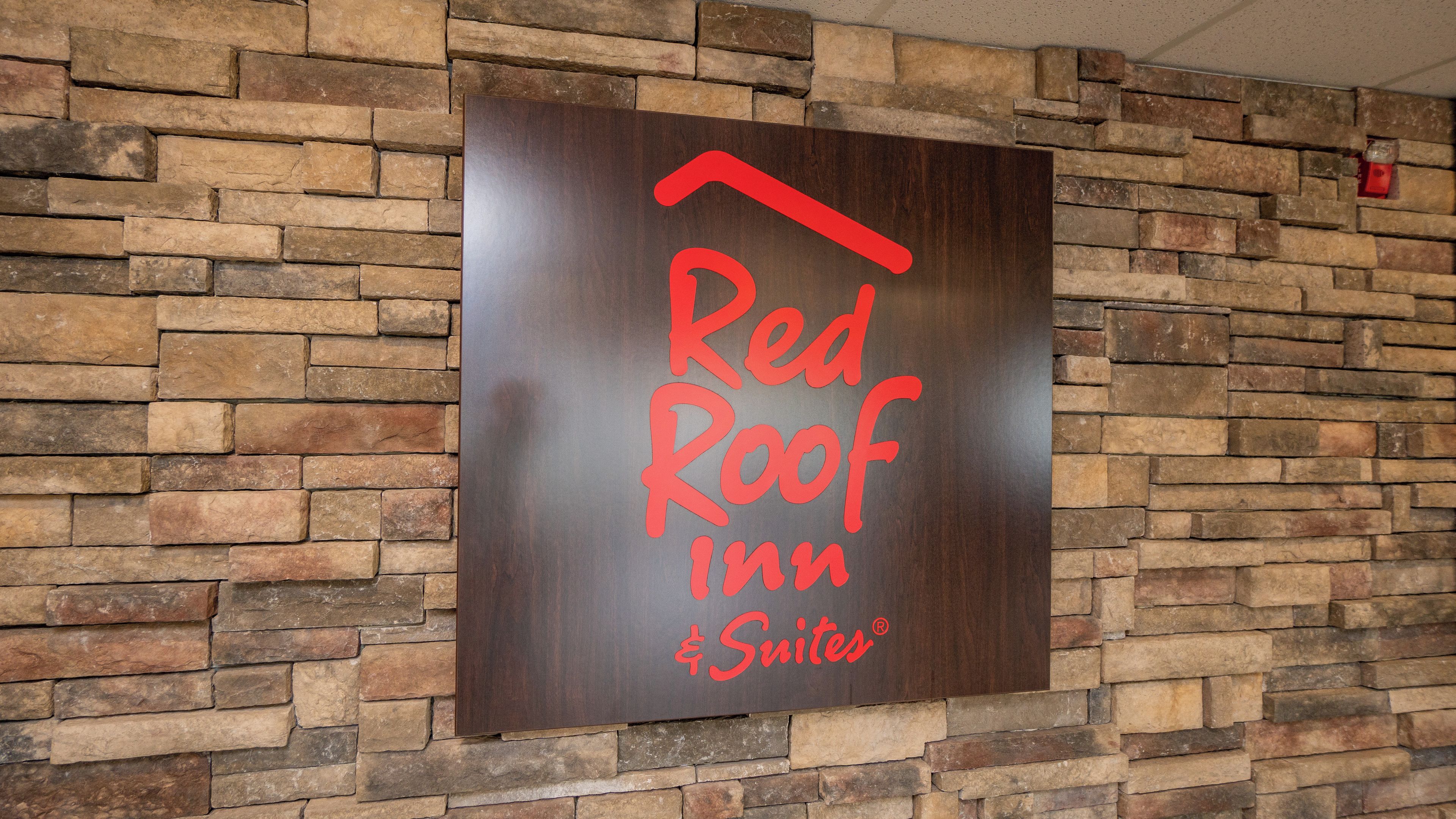 Placa da Red Roof Inn Suites em frente a uma parede de pedra.