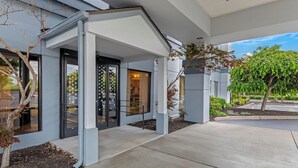 A modern building with a covered entrance, a glass door, and a small garden area. - Spark by Hilton Cincinnati Airport South (Florence)