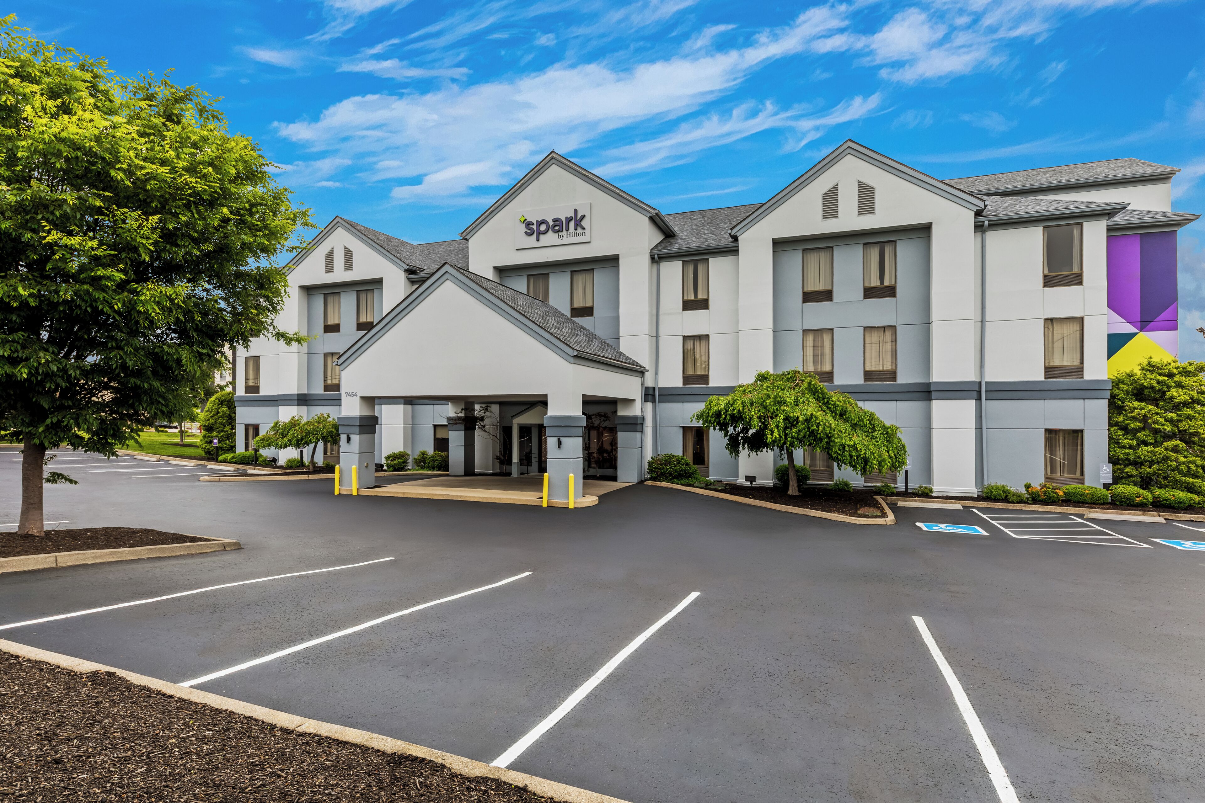 A hotel with a modern design, a parking lot, and a clear sky.