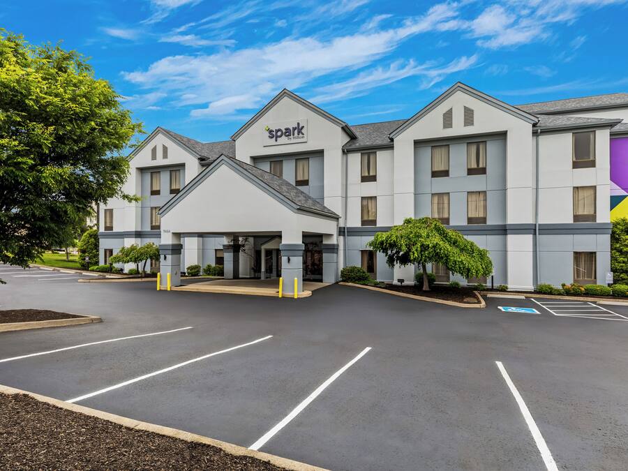 Um hotel com design moderno, estacionamento e céu claro.