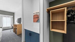 A hotel room with a desk, chair, and a wardrobe with hanging space. - Spark by Hilton Cincinnati Airport South (Florence)