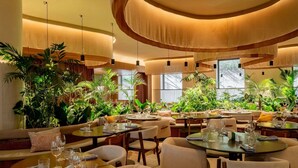 Un restaurant avec des tables rondes, des chaises et des plantes en pot.