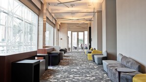Un hall d’entrée moderne avec un sol à motifs, des espaces de détente et de grandes fenêtres.