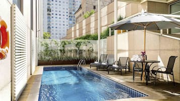 Una piscina al aire libre, sillones reclinables de piscina