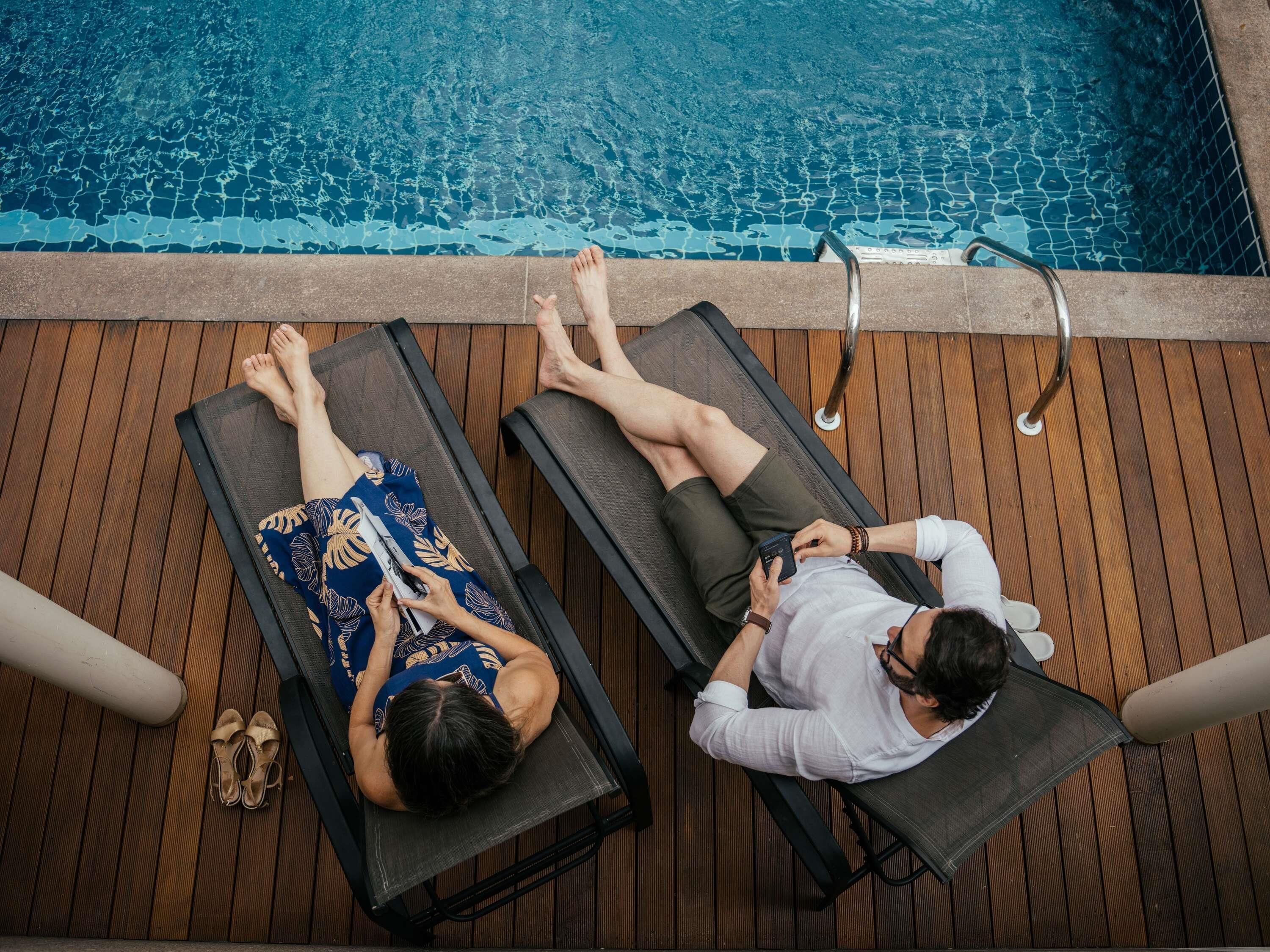 Dos sillones junto a una piscina con terraza de madera.