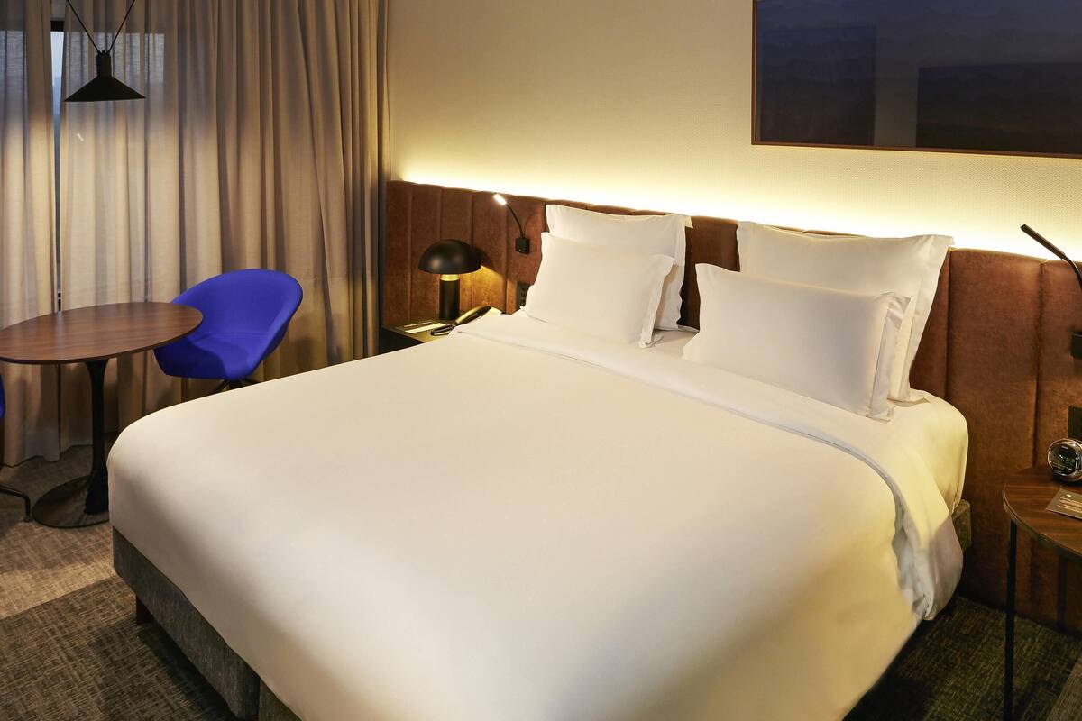 Een hotelkamer met een groot bed, een bureau, een stoel en een lamp.