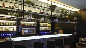 Un espace bar doté de plusieurs étagères remplies de bouteilles d’alcool, d’un comptoir et de plusieurs tabourets de bar.
