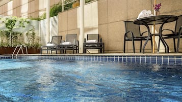 Una piscina al aire libre, sillones reclinables de piscina