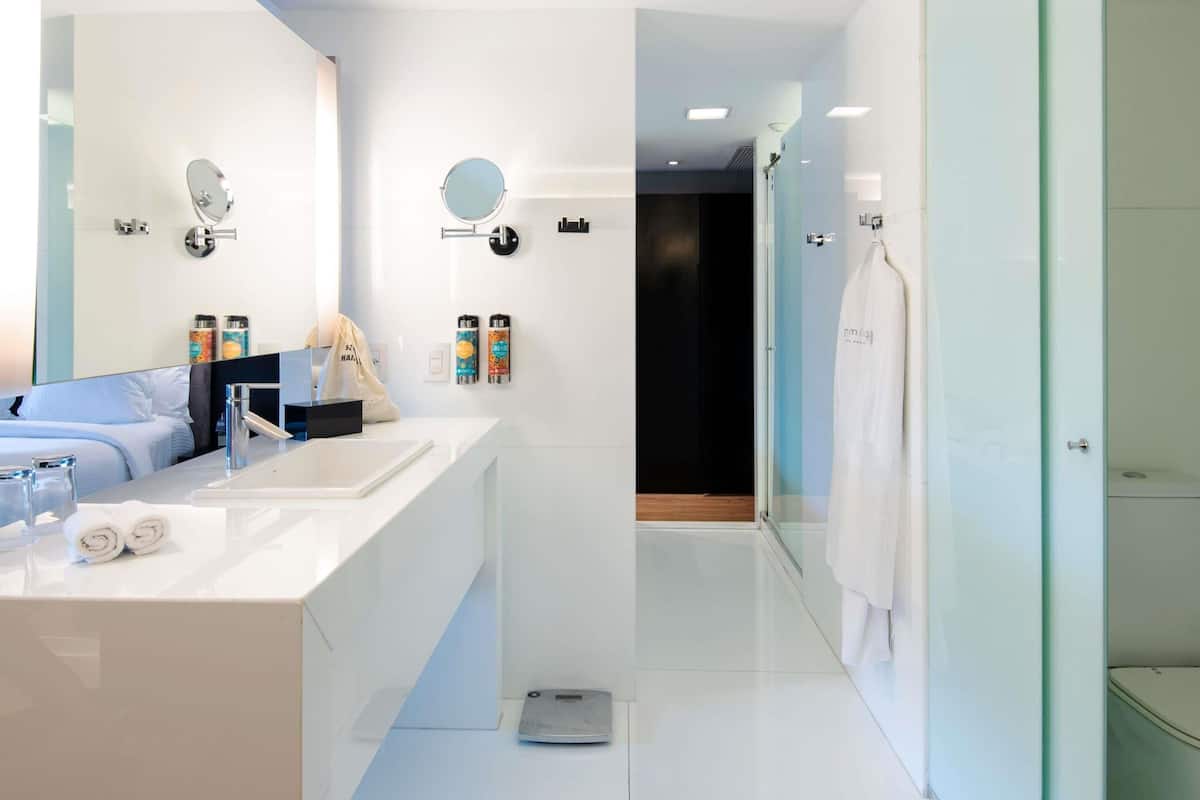 Een moderne badkamer met een grote spiegel, twee wastafels en een douchegedeelte.