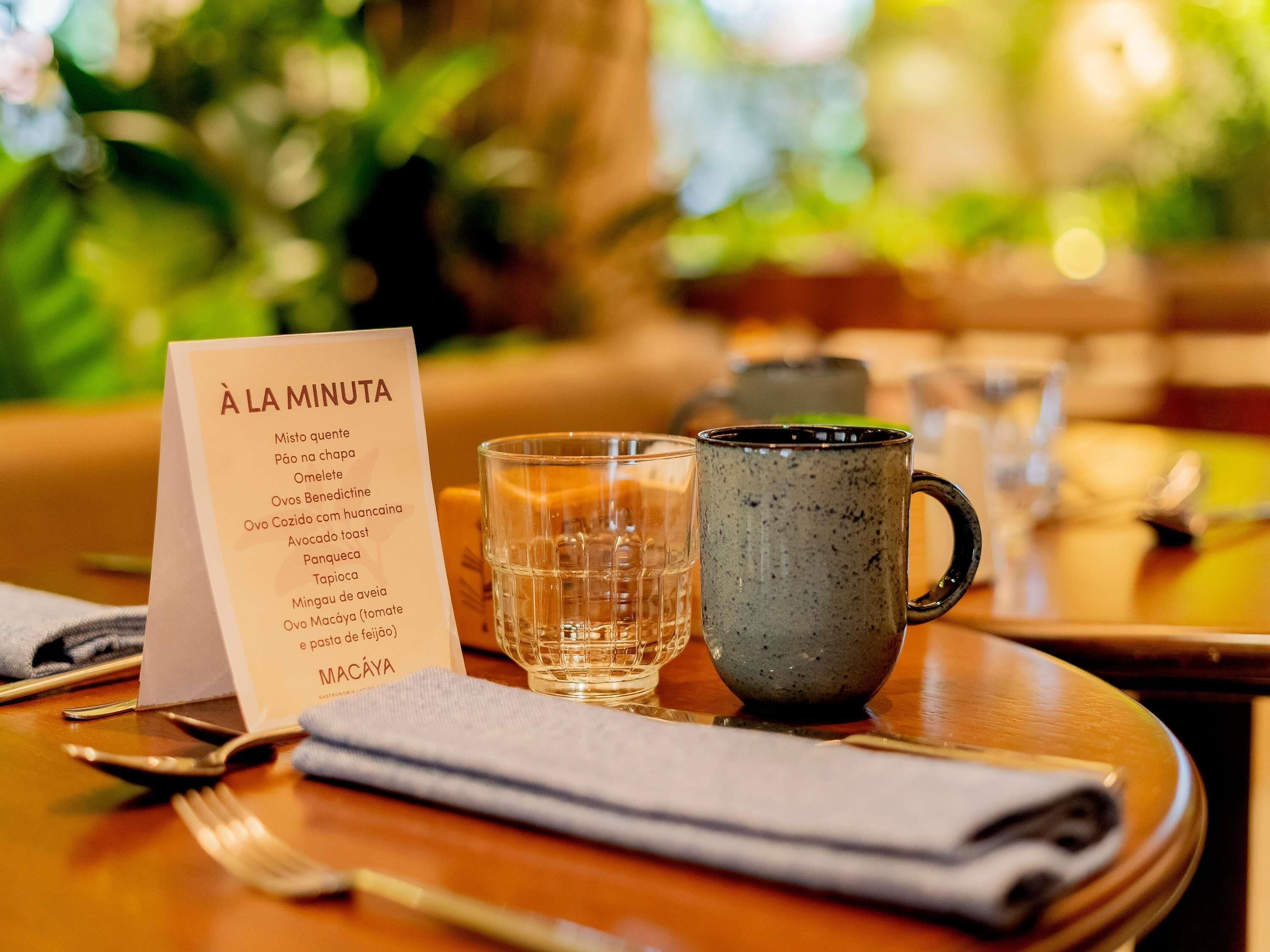 Una mesa de restaurante con un menú, una copa y una taza.