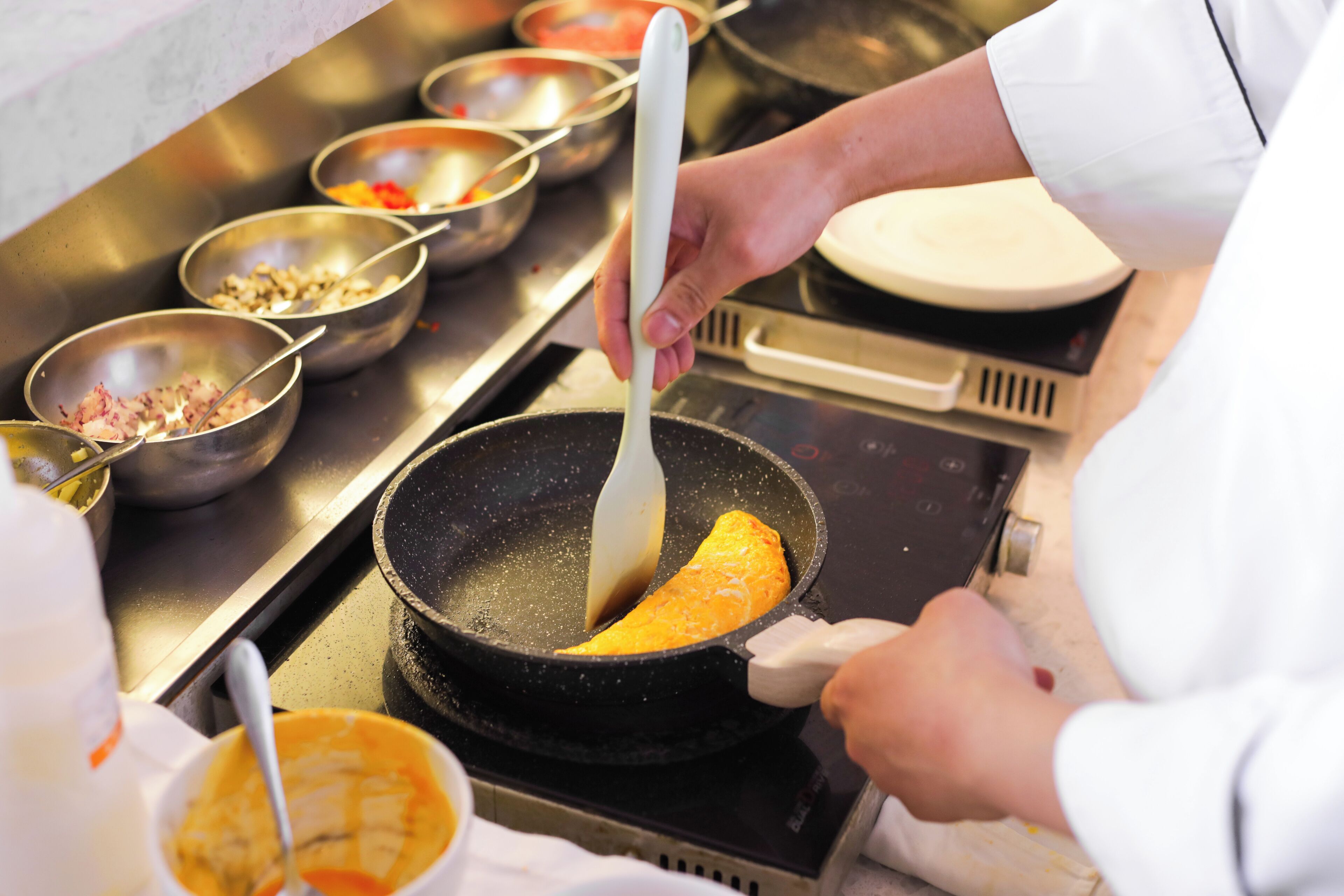 A chef cooking in a professional kitchen with various ingredients and utensils.
