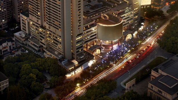 Un edificio a grattacielo con un tetto dalla forma curva caratteristica, circondato da altri edifici alti in un panorama urbano.