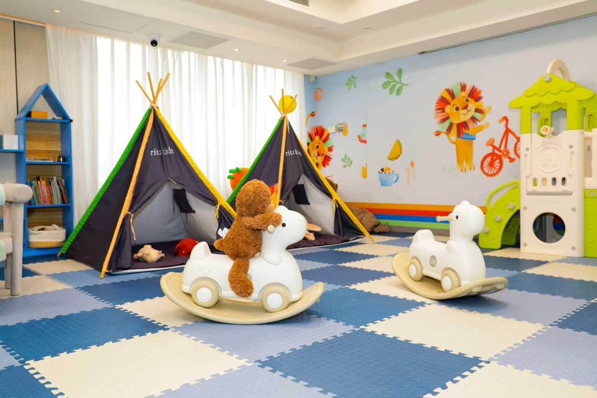 A children's playroom with two tents, a rocking horse, and a playhouse.