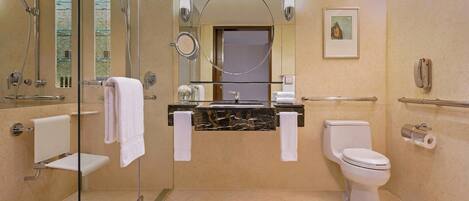 Un baño moderno con cabina de ducha de vidrio, lavamanos de mármol, inodoro y mampara de vidrio.