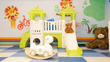 A children's play area with a slide, a small train, and a teddy bear.