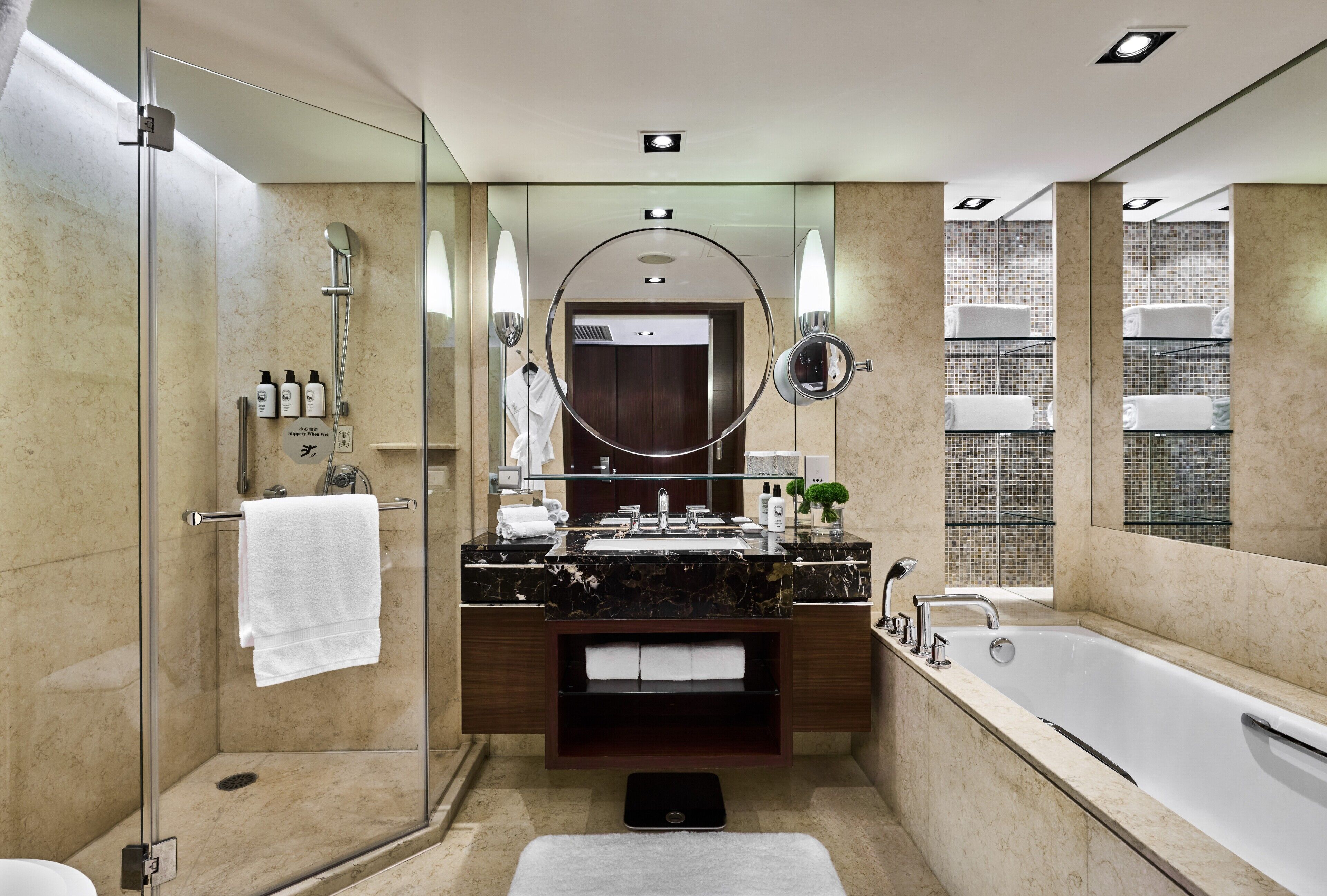 Un baño moderno con ducha envuelta en vidrio, un espejo grande, una bañera y un tocador con encimera de mármol.