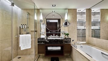 Un baño moderno con ducha envuelta en vidrio, un espejo grande, una bañera y un tocador con encimera de mármol.