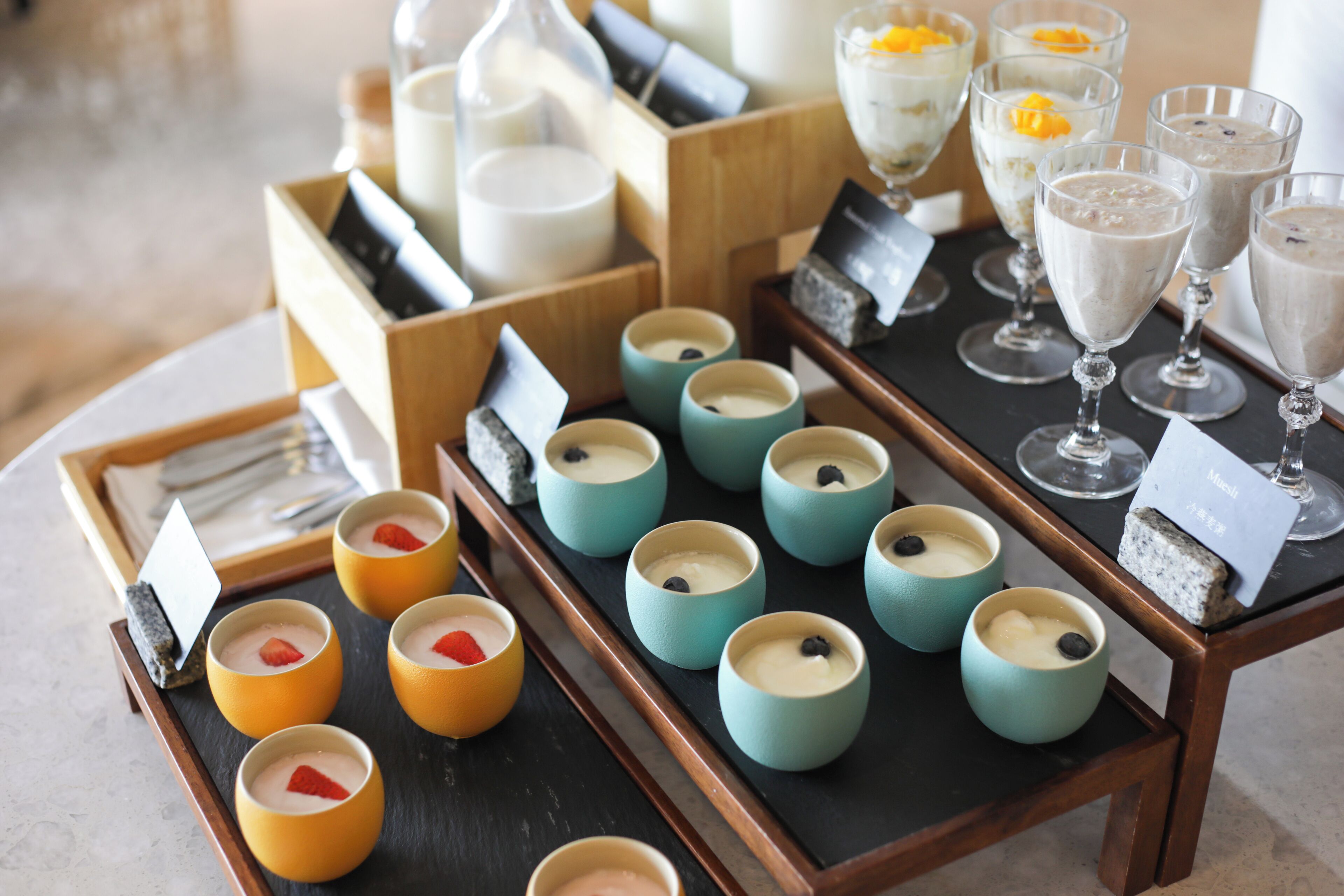 A variety of desserts and beverages arranged on a table, including small cups with toppings and larger glasses.