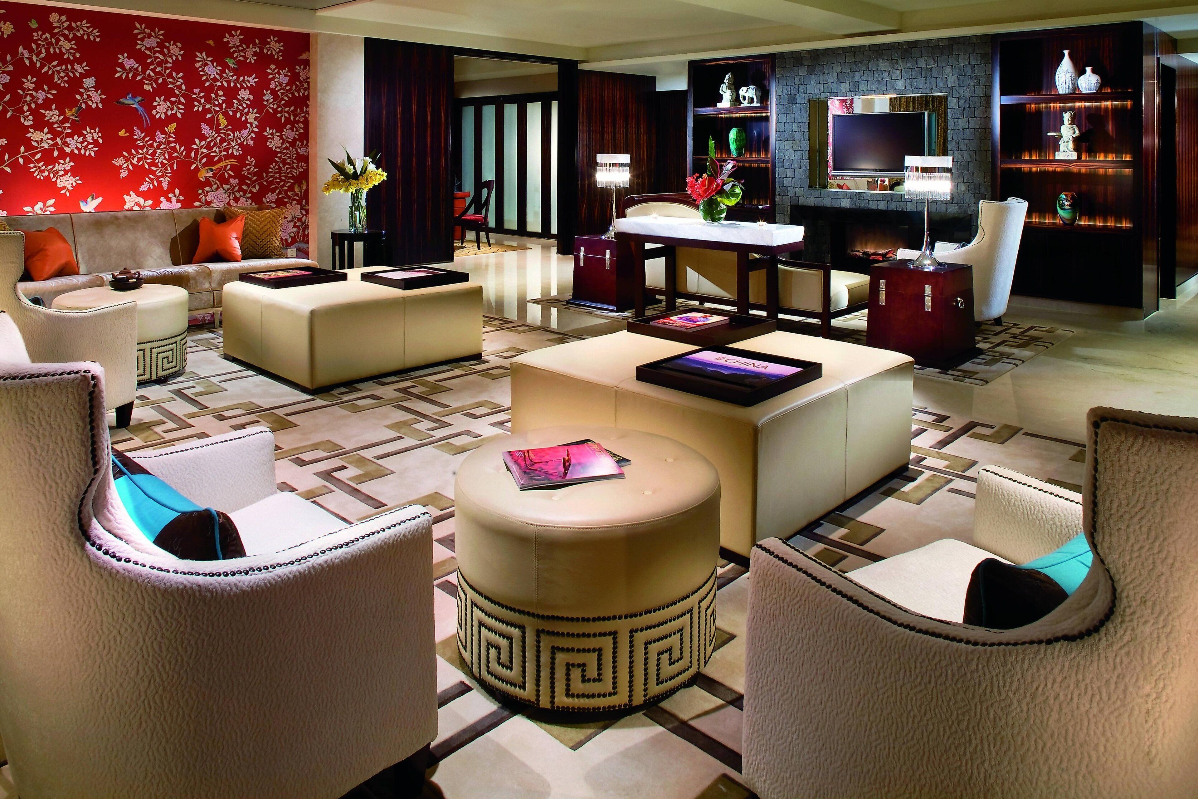 Una sala de estar moderna con un sofá, un reposapiés y sillones, un televisor y una estantería.