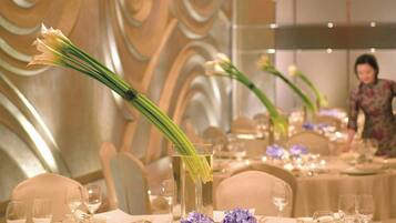 Mesa de banquete dispuesta para un evento formal, con una pared decorativa al fondo.