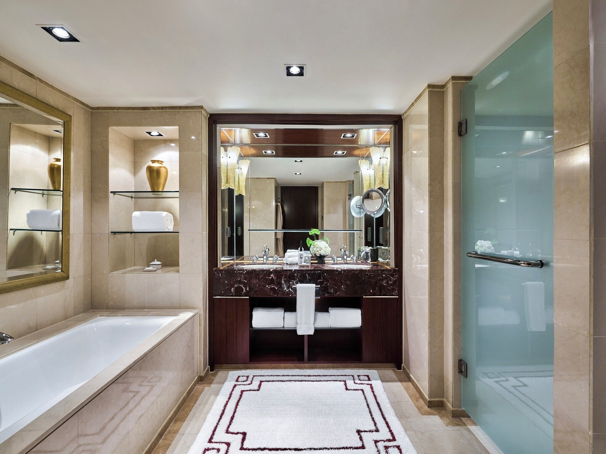 A modern bathroom with a large mirror, a bathtub, and a glass shower enclosure.