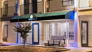 A Days Inn with a blue door, a bench outside, and a small tree in the front. - Days Inn by Wyndham Simpsonville (Simpsonville)