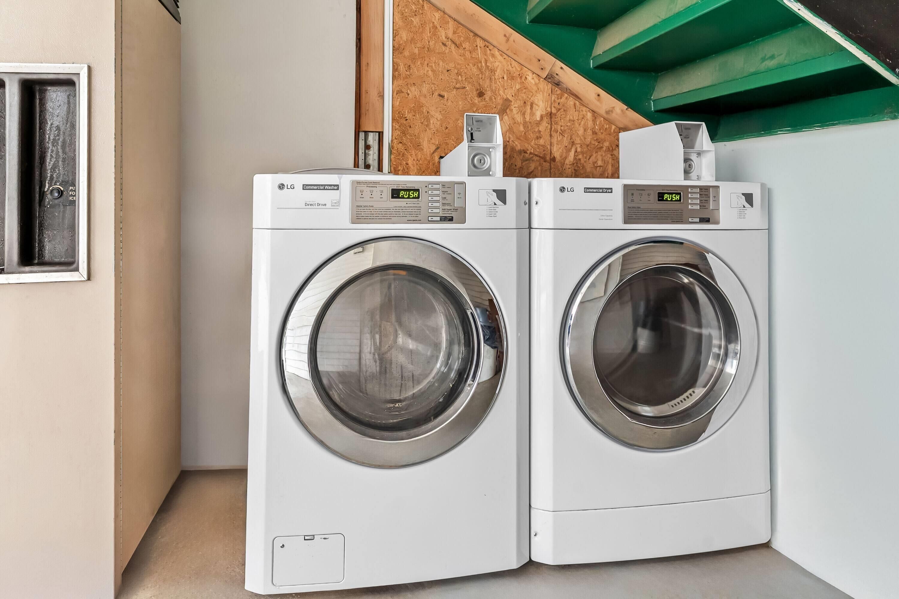 Two white LG commercial washers in a corner with a wooden wall and a green ceiling.