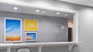 A reception area with a counter, framed artwork, and a 'Hello Sunshine' sign. - Days Inn by Wyndham Simpsonville (Simpsonville)