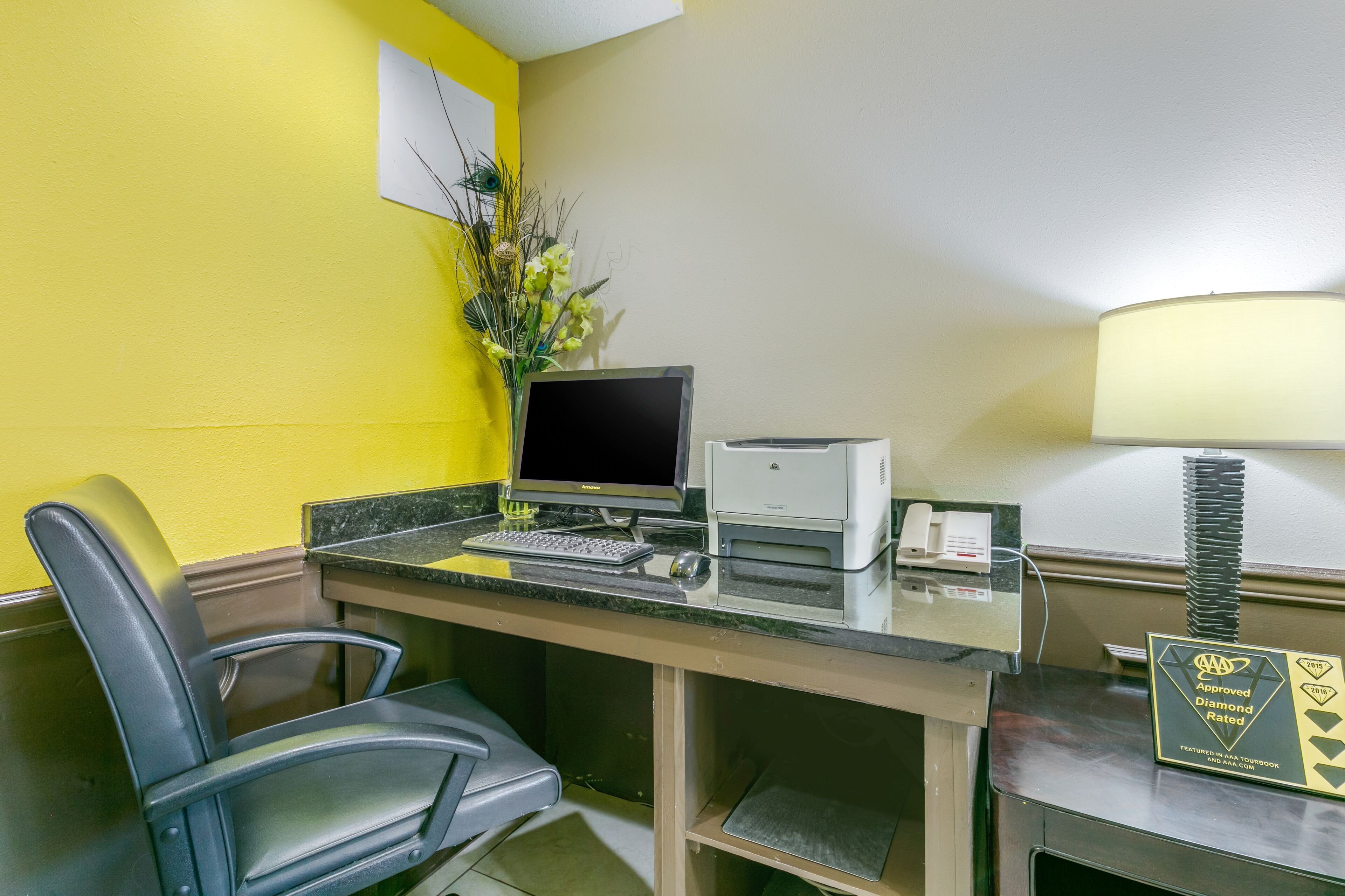 A hotel reception desk with a computer, printer, and a sign indicating it is AAA Approved and Diamond Rated.
