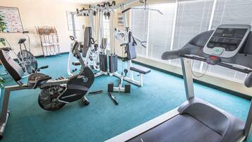 A gym with a treadmill, elliptical, and weight machines.