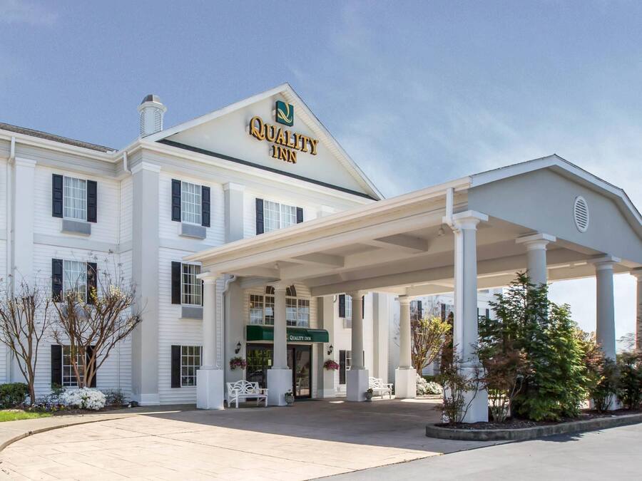A white building with a covered entrance, columns, and a sign that reads 'Quality Inn.'