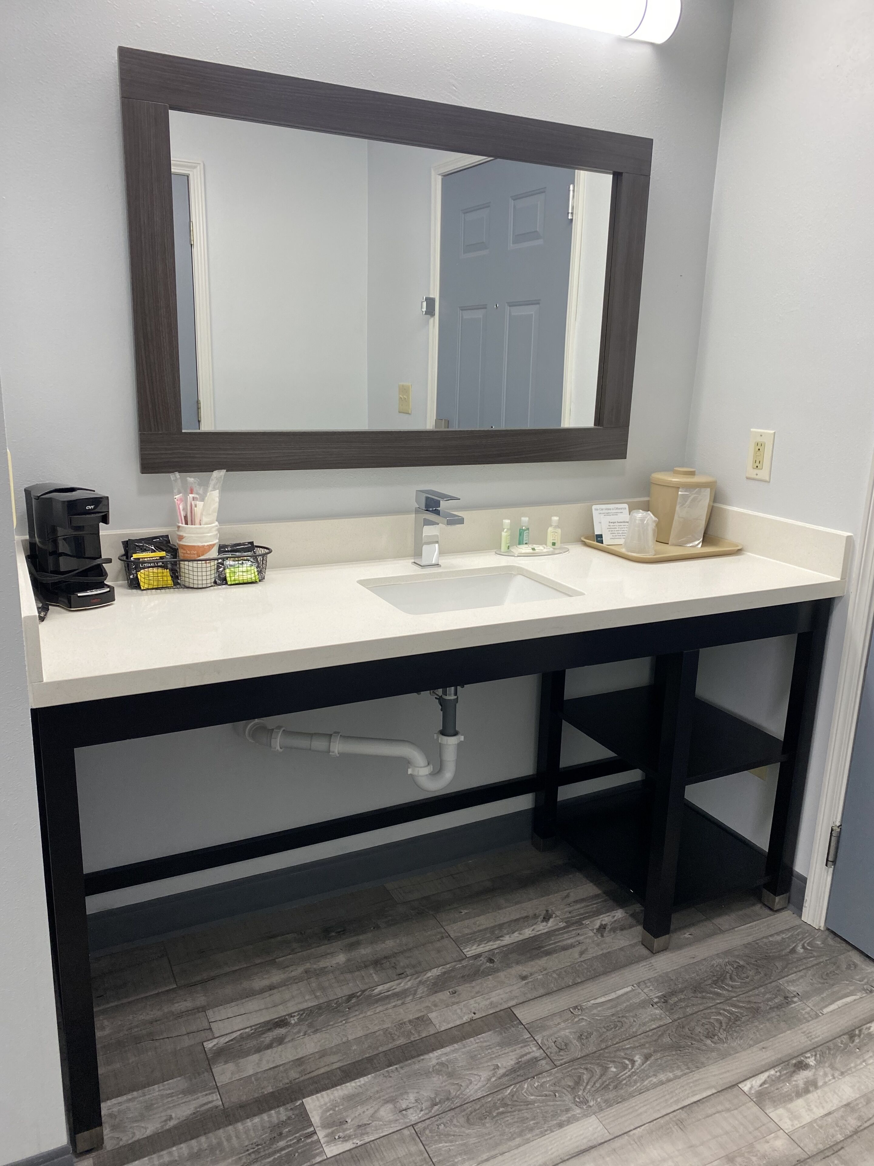 A bathroom with a white sink, dark wooden vanity, and a large mirror.